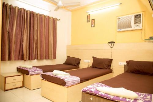 ムンバイにあるSrujan Sarai Service Apartmentのベッドが2つと窓のある部屋