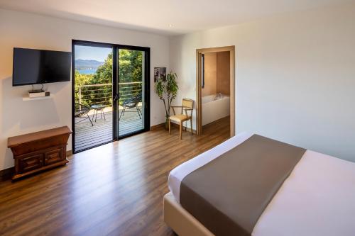 una camera con letto e un balcone con TV di Hotel Restaurant Mariosa a Porto Vecchio