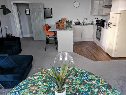 a living room with a table and a kitchen at Upmarket 2 bedroom apartment with sea views in Torquay