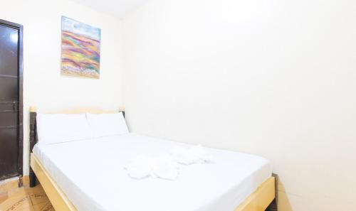 un letto bianco in una stanza con un dipinto sul muro di Golden Pegasus Hotel La Union by RedDoorz a San Juan