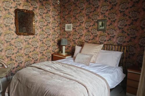 Bett in einem Schlafzimmer mit Blumentapete in der Unterkunft Charming Georgian Cottage with Private Sun Terrace in Bath