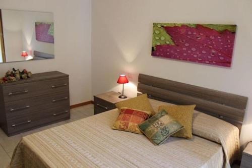 een slaapkamer met een bed met 2 kussens en een dressoir bij Casa di Chiara in Peschiera del Garda