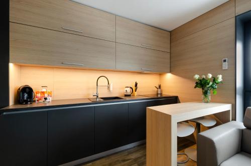 a kitchen with wooden cabinets and a sink and a table at LupoApartments z Klimatyzacją do wyboru z Jacuzzi Pole Dance Parking Dostęp na Kod in Łódź