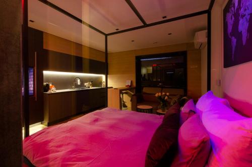 a bedroom with a large pink bed with a person sitting on it at LupoApartments z Klimatyzacją do wyboru z Jacuzzi Pole Dance Parking Dostęp na Kod in Łódź