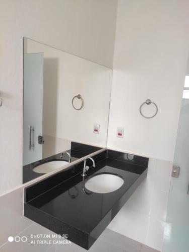 La salle de bains est pourvue de 2 lavabos et d'un miroir. dans l'établissement Hospedagem Casa Branca Localizada em um bairro nobre de Capitólio, Escarpas do Lago, à Capitólio