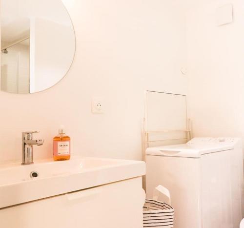 une salle de bain blanche avec un lavabo et un miroir dans l'établissement Vivien Durand - Boutique Aparthotel au cœur de Bordeaux, à Bordeaux