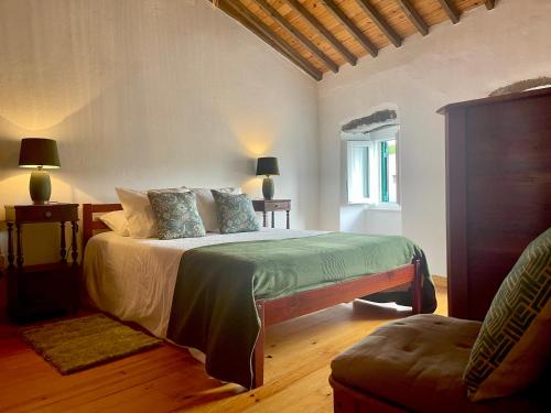a bedroom with a bed and a chair and a window at Casa O Refúgio in Lagoa