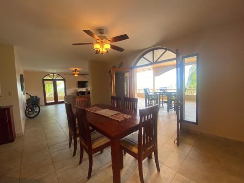 a dining room with a table and chairs and a ceiling fan at Los Porticos in Placencia Village