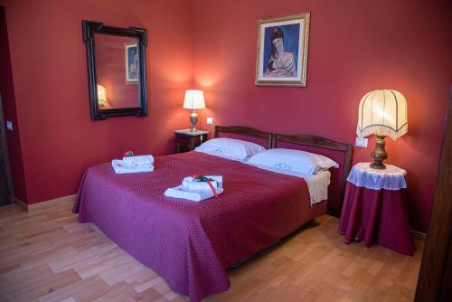 1 dormitorio con 1 cama con paredes rojas y espejo en Casa Senatore, en Capestrano