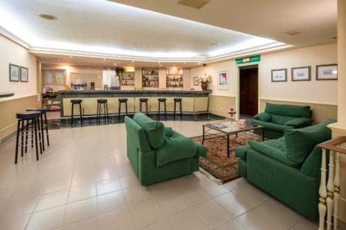 a living room with green couches and a bar at Motel Jardin in Oleiros