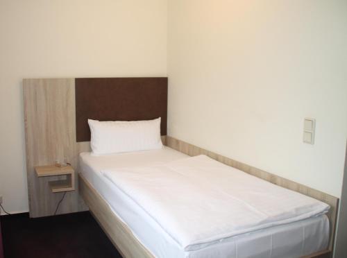 a bed in a room with a white bedsheet at Hotel Stadt Kamen in Kamen