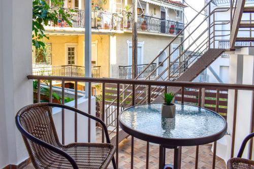 a table and chairs on a balcony with a staircase at La Maison Plakes 3 BDR Apt in Skiathos