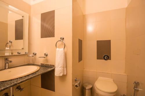 Un baño con lavabo, inodoro y espejo. en goSTOPS Mukteshwar, en Mukteshwar