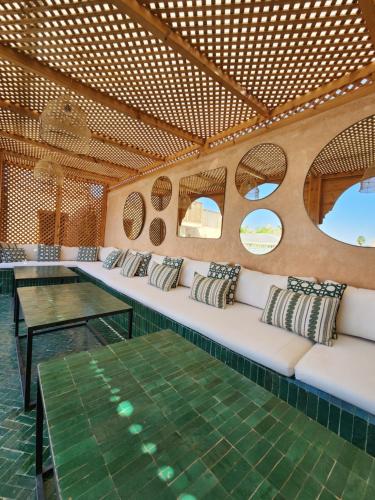 Cette chambre comprend des canapés blancs, une table et des fenêtres. dans l'établissement Riad Le Saadien, à Marrakech