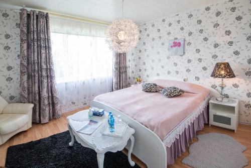 1 dormitorio con cama, mesa y lámpara de araña en Muru Guesthouse, en Kuressaare