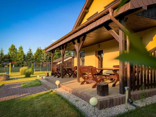 a porch of a house with a picnic table and benches at Prosportówek - Powidz - Dom Bliźniak nad Jeziorem z Dużym Ogrodem in Powidz