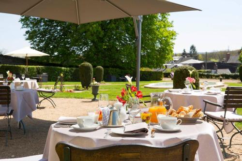 a table with white table cloths and an umbrella at Château de Noizay - ChâteauZen in Noizay