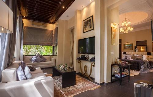 een woonkamer met een bank en een tv bij Le Palais Rhoul and Spa in Marrakesh