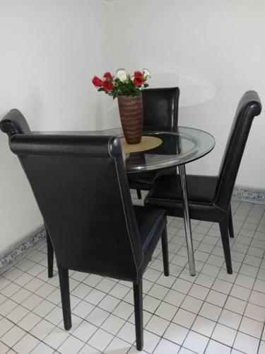 a table with two chairs and a vase with flowers on it at Beautiful appartement 2 beds 2 toilets kitchen in Bonamakolo