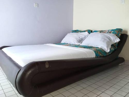 a bed with a black frame in a room at Beautiful appartement 2 beds 2 toilets kitchen in Bonamakolo