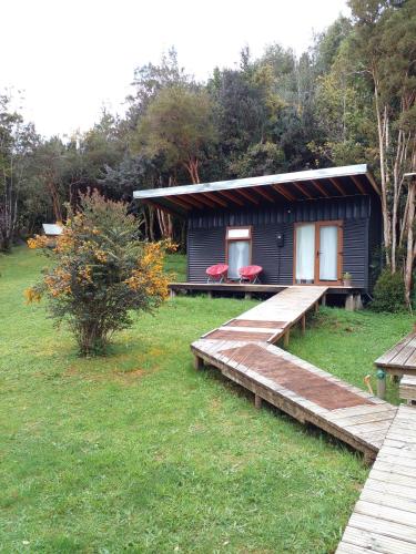 a small house with a wooden porch and a deck at Eco Cabañas Wanderlust in Puerto Puyuhuapi
