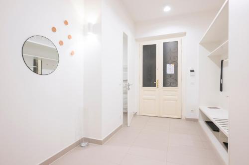 a white hallway with a mirror and a door at Luxury Suites Liechtenstein in Vienna