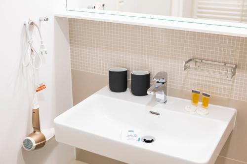 a white bathroom sink with two cups on it at Luxury Suites Liechtenstein in Vienna