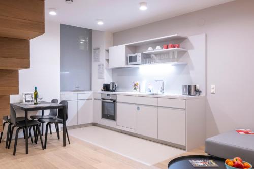 a kitchen with white cabinets and a table and chairs at Luxury Suites Liechtenstein in Vienna