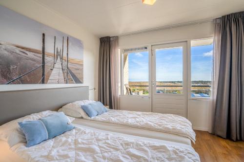 ein Schlafzimmer mit einem Bett und einem großen Fenster in der Unterkunft Appartementencomplex Juliana 122 in De Koog