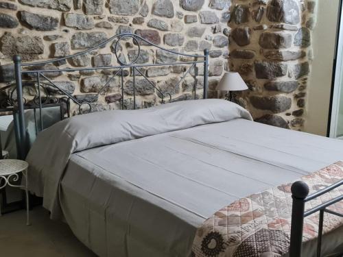 Cama en habitación con pared de piedra en Rifugio dei Saraceni en Vallecrosia