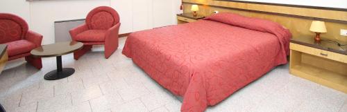 a bedroom with a red bed and two chairs at Hotel Croce Di Malta in Novara