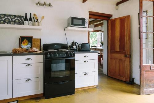 a kitchen with a black stove and white cabinets at Beaumont Family Wines in Botrivier