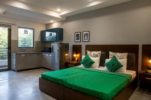 a bedroom with a green bed and a kitchen at Perch Service Apartment DLF Cyber City in Gurgaon