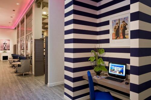 a office with a striped wall with a computer on a desk at Estilo Fashion Hotel Budapest in Budapest
