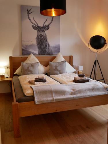 1 dormitorio con 1 cama con una pintura de ciervo en la pared en 2 Zimmer Ferienwohnung „Schliersberg“ en Schliersee