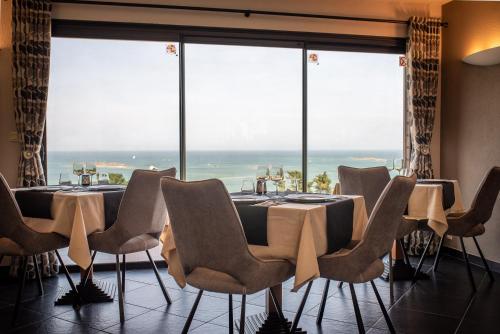 une salle à manger avec une table, des chaises et des fenêtres dans l'établissement Domaine Buhez Nevez, à Trélévern