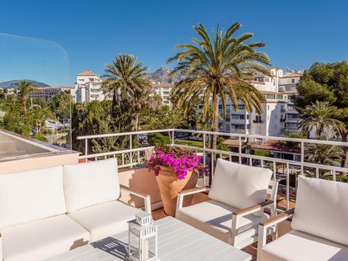 a balcony with white chairs and palm trees at Ático de 2 dormitorios en Andalucía del mar in Marbella