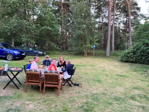 un gruppo di persone seduti a un tavolo in un cortile di Ljunghusen Holiday Inn Cottage a Ljunghusen