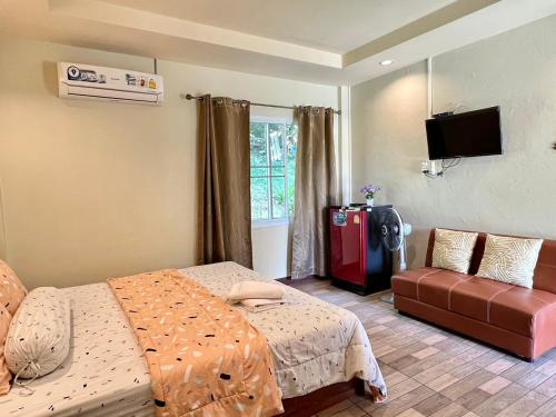 a bedroom with two beds and a couch and a television at นพรัตน์การ์เด้นฮิลล์ in Uthai Thani