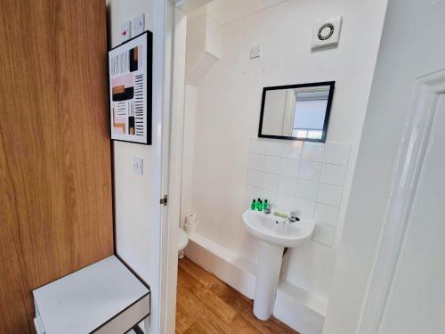 a white bathroom with a sink and a mirror at Midewell Court by Kasar Stays in Otford