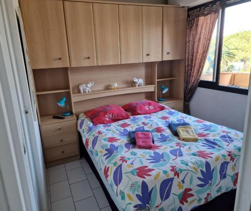 a small bedroom with a bed with red pillows at Résidence Les Mers du Sud Port Argelès in Argelès-sur-Mer