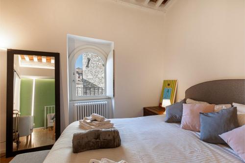 a bedroom with a bed with a mirror and a window at Dimora Casina dell'abbondanza in Gubbio