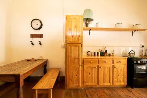 Una cocina con armarios de madera y una mesa y un reloj. en Morendat House, en Graaff-Reinet