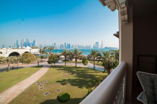 a balcony with a view of the ocean and palm trees at 1-bedroom apartment with pool in Dubai