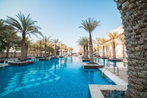 a swimming pool with palm trees in a resort at 1-bedroom apartment with pool in Dubai