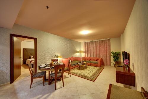 a living room with a couch and a table with chairs at Al Manar Grand Hotel Apartment in Dubai