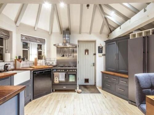 uma grande cozinha com armários cinzentos e electrodomésticos em Dreamwood Cottage Luxury Hottub Retreat em Crigglestone