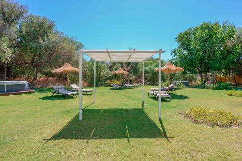 - un pavillon avec des chaises et des parasols dans un parc dans l'établissement Hotel Maison del Sole, à Terra Mala