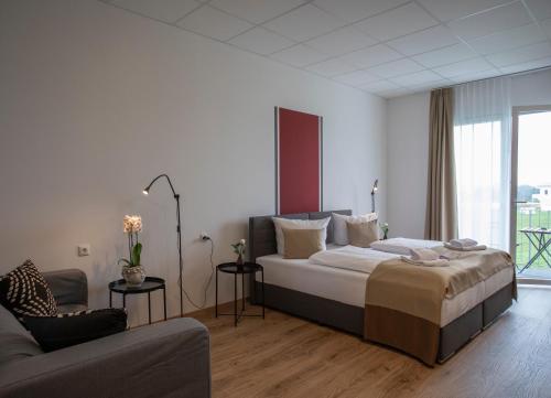 a bedroom with a large bed and a couch at B Home Apart Hotel by Alpha in Bogen