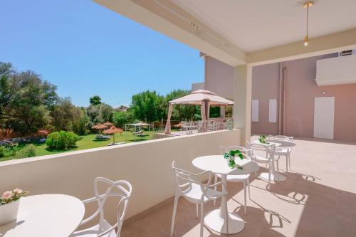 un patio con tavoli e sedie bianchi e una grande finestra di Hotel Maison del Sole a Terra Mala